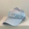 Detailed close-up of light blue satin baseball cap with white gothic letter embroidery. - 54-59 Adjustable / Light Blue