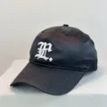 Close-up detail of black satin baseball cap with white embroidered letter for outdoor sun protection. - 54-59 Adjustable / Black