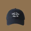 Detailed view of the dark blue baseball cap with white cursive letter embroidery text. - Adjustable / Navy Blue