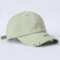 Detailaufnahme der hellgrünen Distressed-Baseballcap mit Metall-Piercingringen und cooler Stickerei. - Einheitsgröße / Hellgrün