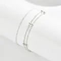 Cavigliera minimalista argentata a doppio strato con perle e catena ritorta, primo piano. - Argento