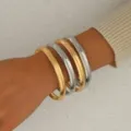 Bracciali rigidi lisci in metallo color oro e argento al polso, stile punk chic immagine principale. - Due colori