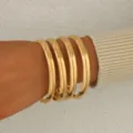 Meraviglioso set di quattro bracciali rigidi dorati e lisci in stile geometrico elegante. - Oro