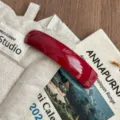 Detailed view of the red curved acetate hair clip, showing glossy finish and minimalist design. - Red