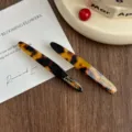 Detailed close-up of tortoise shell acetate hair clips featuring elegant gold lettering. - 2 Pieces/Pack / Dark Leopard Print