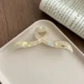 Close-up detail shot of the irregular iridescent acetate large hair claw clip on white tray. - Mermaid Color