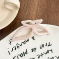 Primer plano de una pinza de pelo de acetato rosa con forma de mariposa en plato cerámico. - Rosa Tierno