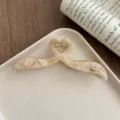 Detailed close-up view of an irregular acetate hair claw clip on a stylish ceramic tray. - Beige Yellow