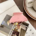 Detailed close-up of a stylish pink acetate hair claw clip showcasing elegant texture and design. - Pink