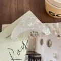 Detailed view of translucent iridescent hair claw clip with elegant curved shape and secure teeth. - White
