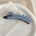 Detailed close-up shot of a cute blue cat banana hair clip with black bow and gold text. - Blue