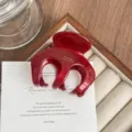 Detailed close-up of the red acetate hair claw clip, showing glossy finish and texture. - Burgundy