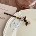 Detailed shot of Korean style tortoise shell acetate bow hair clip, elegant retro flat lay. - Dark Leopard Print