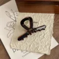Close-up of elegant brown acetate hair claw clip, showcasing exquisite handmade texture and details. - You Shape Cross