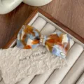 Detail shot of French style rhinestone bow hair clip, acetate material with elegant finish. - Blue/Orange