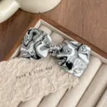 Detail shot of a French rhinestone bow hair clip with black white swirl acetate design. - Black and White
