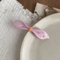 Close-up detail of the sweet pink leaf-shaped bow hair clip with orange ring accent. - Light Purple
