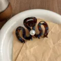 Detail shot of a brown tortoise shell hair claw clip featuring a chic center pearl accent. - Lake Blue Brown