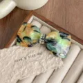 Detailed view of the elegant French acetate bow hair clip with sparkling rhinestones and chic pattern. - Field Green