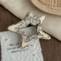 Close-up detail shot of the hollow star hair claw, elegant marble pattern design. - Ink Grey
