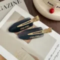 Close-up detail of sleek acetate hair clip with gold metal snap, stylish dark design. - Pair (With Cardboard) / Ink Pattern