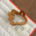 Gros plan détaillé d'une jolie pince à cheveux marron en résine, idéale pour le coiffage. - Bronze