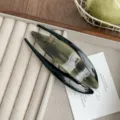 Exquisite acetate hair clip detail showing smooth gradient color and elegant swallowtail design. - Brown Gray Wood Grain