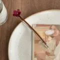 Vista detallada de una pinza para el pelo elegante con flor burdeos en un plato de cerámica. - Flor Morada