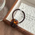 Detailed close-up shot of the vintage tortoiseshell acetate button hair tie texture and elastic band. - Lake Blue Brown