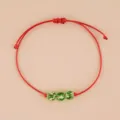 Vista dettagliata del bracciale intrecciato rosso fatto a mano con tre perle di vetro luminose. - Vetro Verde