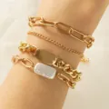 Primo piano dettaglio di un elegante set di bracciali a catena d'oro multistrato con perle. - Oro