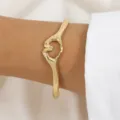 Bracelet jonc cœur double main doré, bijou tendance élégant geste de main vue de détail. - Or