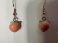 Primo piano dettagliato di orecchini pendenti a forma di graziosa pesca rosa con ganci dorati. - Pesca