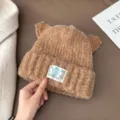 Gros plan détaillé du bonnet chaud en tricot marron avec oreilles de chat et étiquette. - 56-58cm / Café