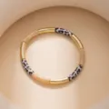 Detailed close-up of geometric color-blocked bracelet featuring gold, beige, and leopard segments. - Beige