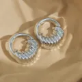 Close-up of silver chunky ribbed hoop earrings, highlighting metallic texture and unique design. - Silver