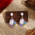 Close-up details of French vintage Monet garden enamel flower and baroque pearl drop earrings. - Purple