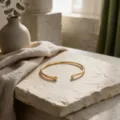 Detalle de brazalete abierto de metal dorada minimalista con suaves curvas geométricas. - Estilo Abierto de Gota de Agua (BH031)