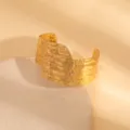 Detailed close-up of a wide gold metal cuff bracelet with unique hammered texture. - Hammered Wavy Style / Gold