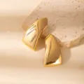 Close-up detail of vintage style gold geometric leaf earrings on textured stone backdrop. - E1535-9