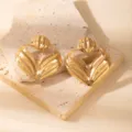 Close-up detail of luxurious gold hollow leaf geometric earrings on stone prop. Elegant design. - E1531-5