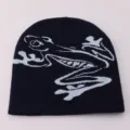 Close-up detail of dark blue knit beanie hat with light blue frog jacquard pattern. - One Size / Black Jacquard Frog