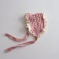 Nahaufnahme der rosa gestrickten Babyhaube mit zarter weißer Borte und weichen Bändern. - Kinder / Rosa