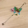 Dettaglio ornamento sospeso acchiappasole in cristallo con farfalla e sfera di cristallo. - Viola