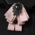 Pink ribbon bow tie brooch with ornate black crystal center and hanging teardrop gemstone. - Pink