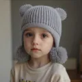 Primer plano detallado de gorro de punto gris para niños con adorables orejas de oso y pompones. - Gris