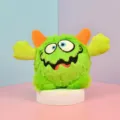 Detailed view of the green plush monster pet toy featuring funny embroidered eyes and orange horns. - Green Large