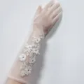 Vista dettagliata di lunghi guanti da sposa bianchi in tulle con ricamo floreale in pizzo e perle. - Strass di Fiore Lungo
