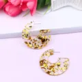 Clear detail shot of C-shaped acrylic earrings with gold glitter flakes, stylish and shiny jewelry. - Color 1