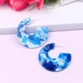 Close-up detail of blue marbled C-shaped acrylic earrings with glitter, minimalist geometric stud. - Color 3